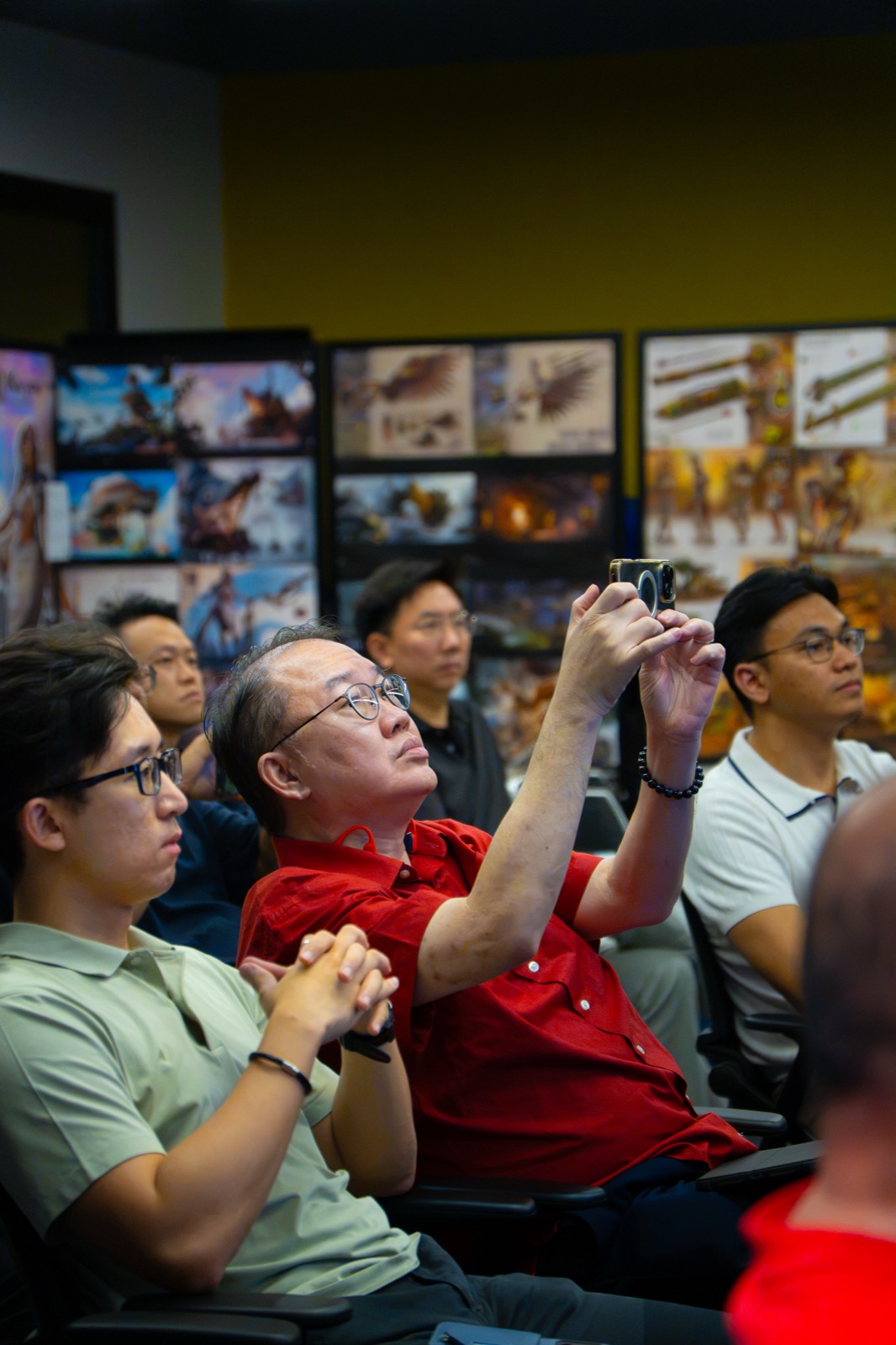 Attendees listening, one photographing the presentation